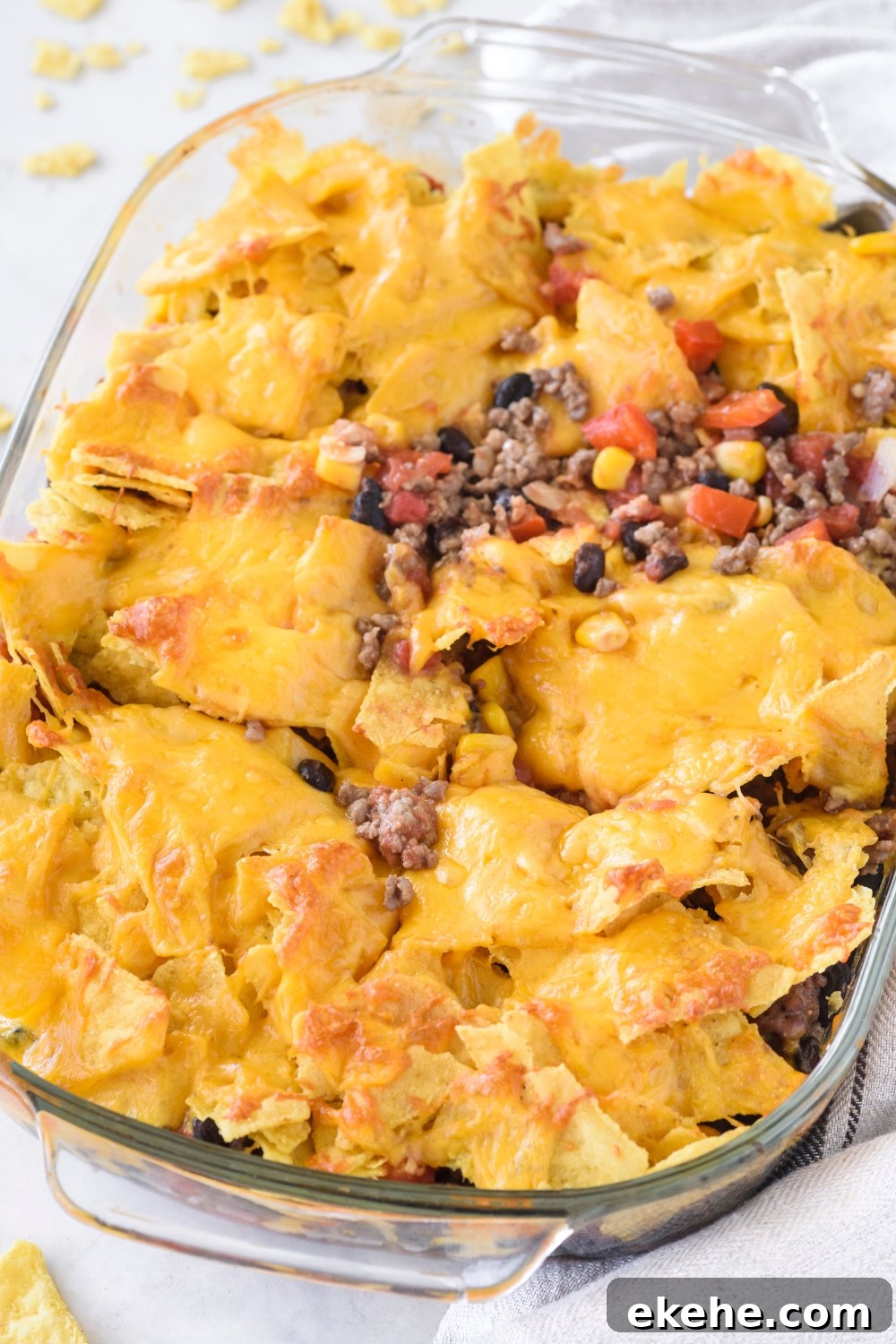 A baking dish filled with freshly baked Tex-Mex casserole covered in melted cheese.