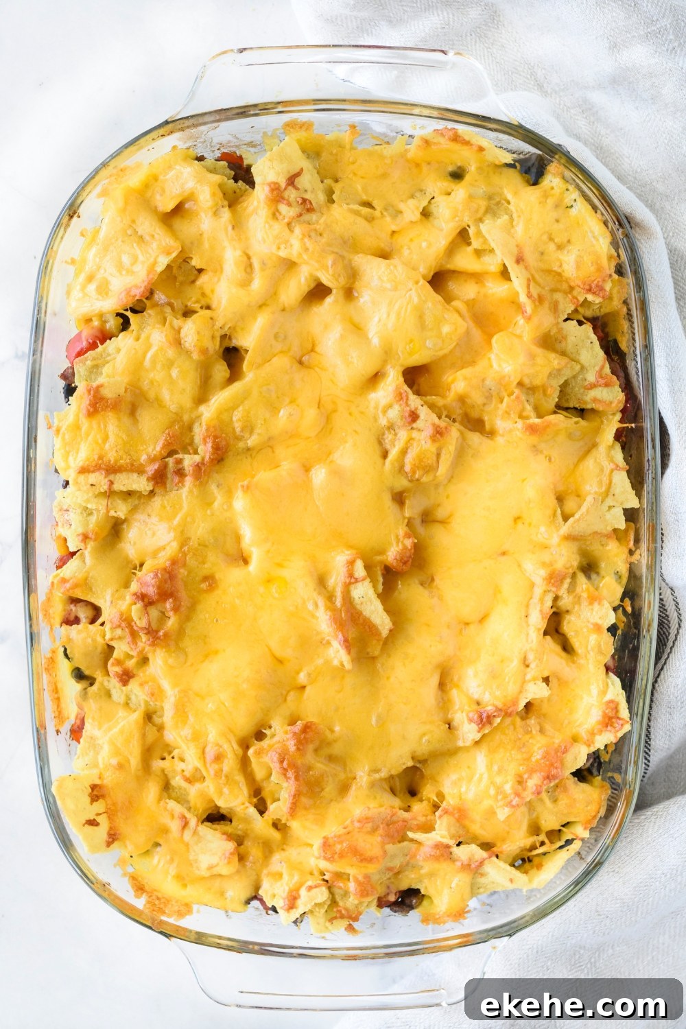 A clear baking dish filled with freshly baked Tex-Mex casserole covered in a layer of melted cheese.