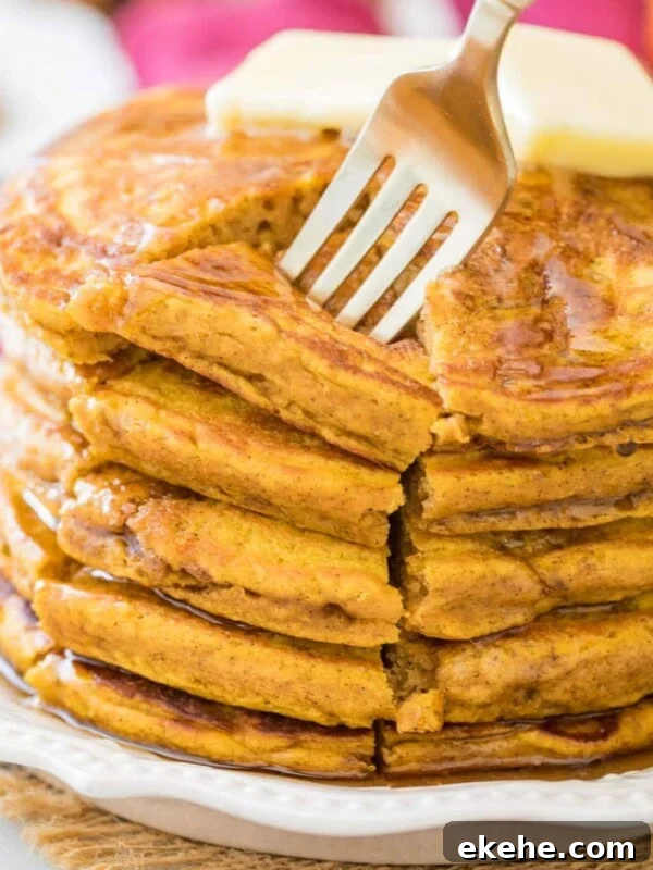 Fluffy Sourdough Pancakes Recipe for Crispy-Edge Breakfast 11 fork piercing a cut section from a stack of thick and fluffy pumpkin pancakes