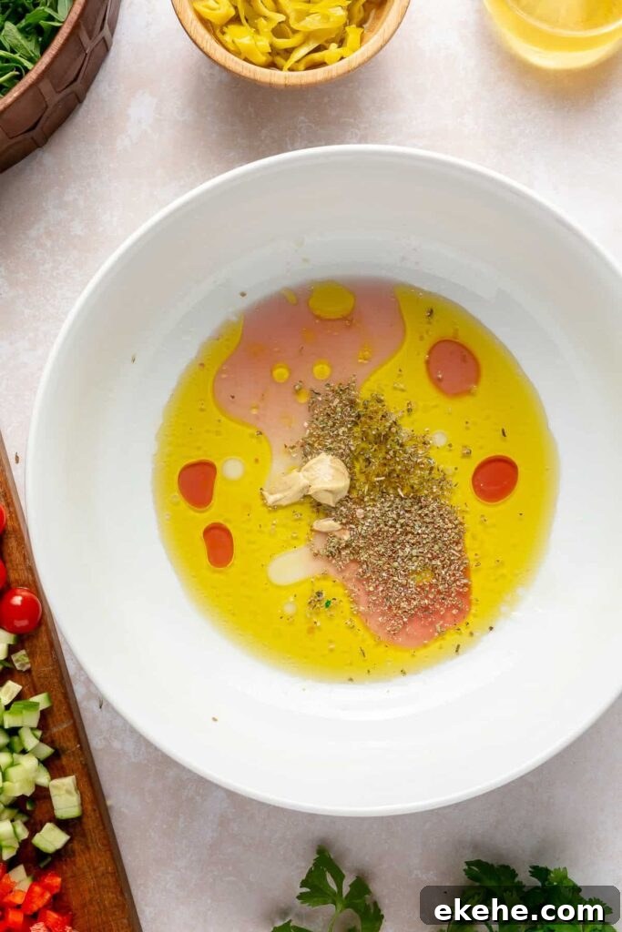 Mixing lemon Greek dressing with olive oil, vinegar, and Dijon mustard in a bowl
