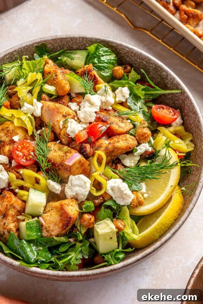 Sheet pan Greek chicken and chickpeas served over fresh Mediterranean salad with feta and herbs