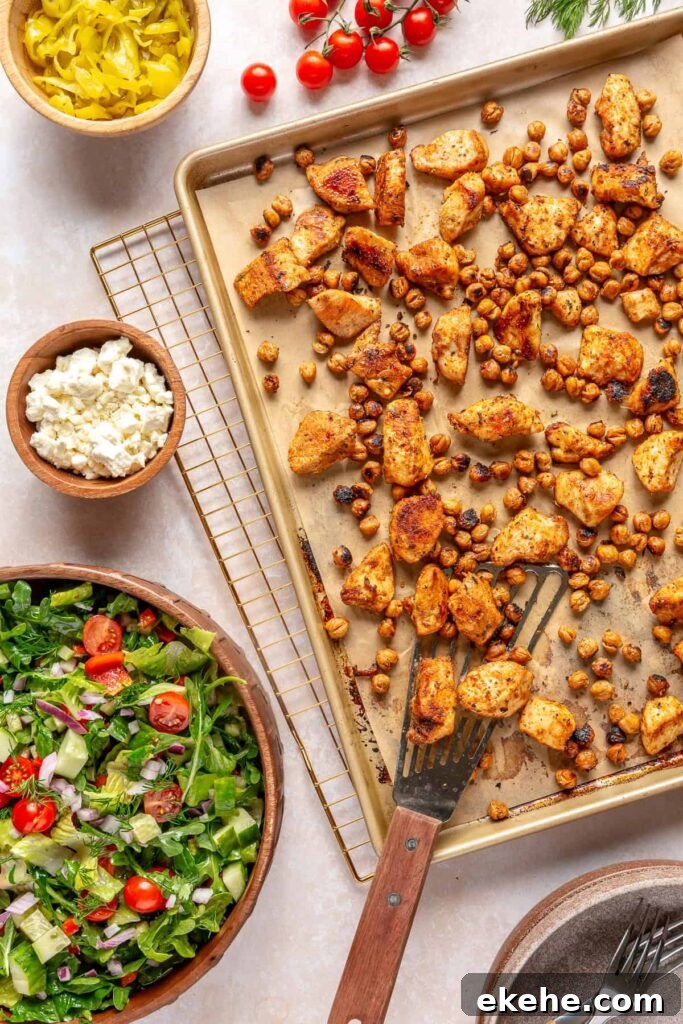 Adding roasted Greek chicken and chickpeas to a fresh salad bowl