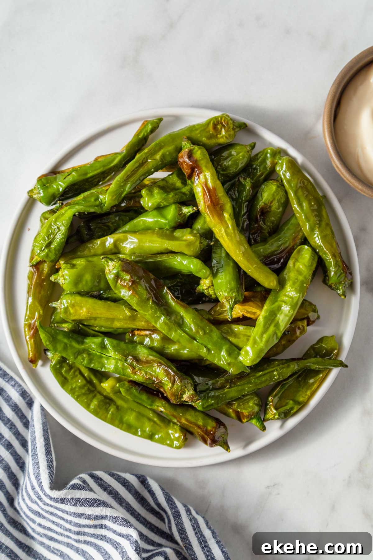 air fryer shishito peppers on a plate with garlic aioli.