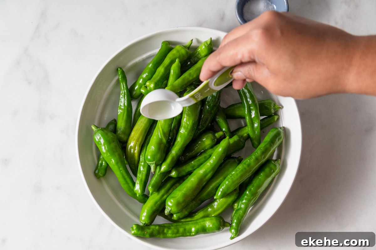 adding oil to shishito peppers.
