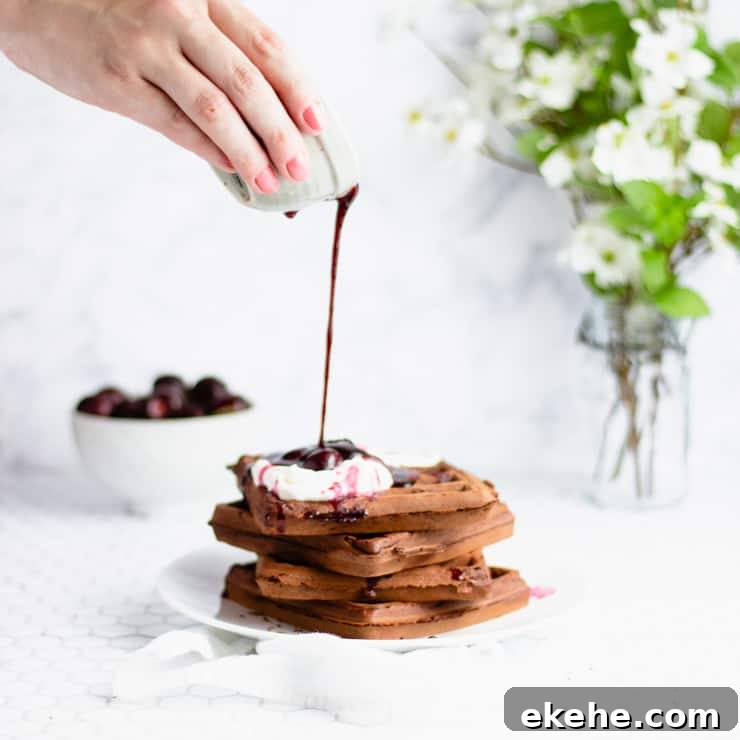 pouring cherry sauce onto chocolate waffles